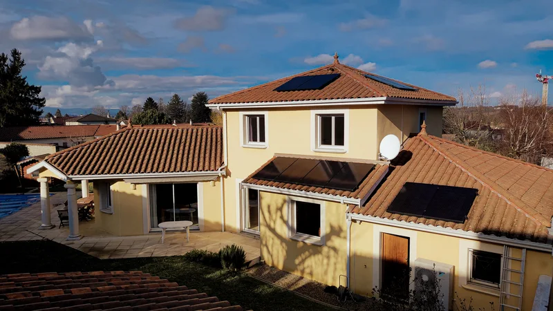 Maison jaune avec ses panneaux solaires sur le pan sud