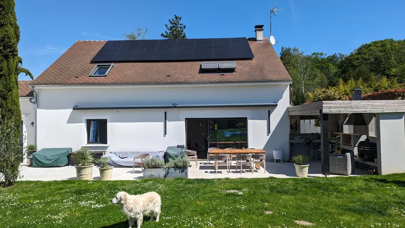 Maison blanche équipée de panneaux, jardin au premier plan
